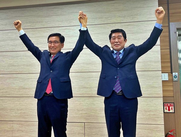 16일 오전 윤건영(왼쪽) 후보와 김진균 후보가 보수후보 단일화를 선언한 뒤 손을 들어 보이는 퍼포먼스를 하고 있다. (사진=윤건영 캠프)