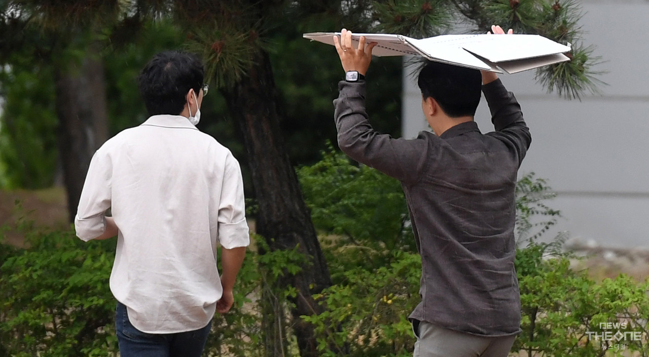 서울·인천·경기 지역에 호우주의보가 내려진 23일 오후 인천시 연수구 송도동에서 한 시민이 종이박스를 이용 비를 피하며 걸어가고 있다. (사진=임순석 기자)
