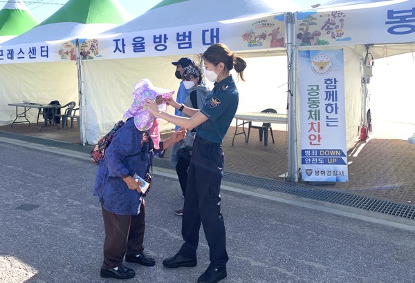 봉화 경찰소 생활안전계 김수완 경사가 할머니에게 해 가리개 를 씌워 드리고 있다(사진='nes THEONE' 정승초 제공))